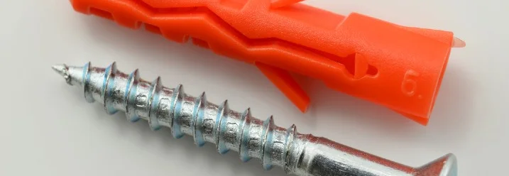 Ein roter Dübel und eine Schraube.